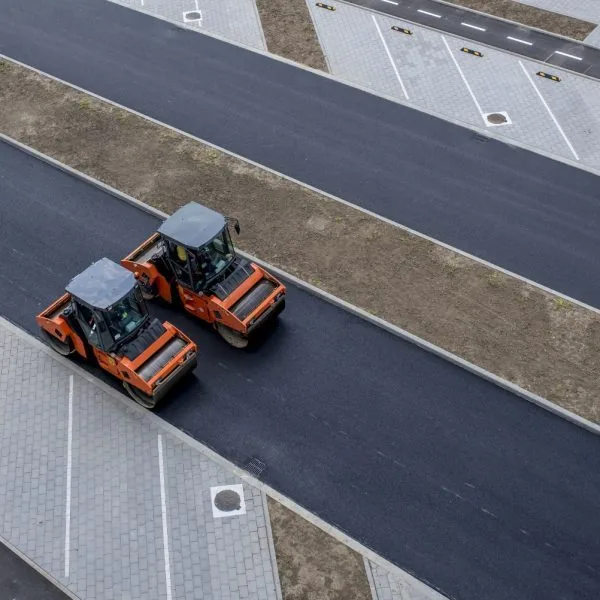 Two rollers smooth out and flatten new asphalt paving.