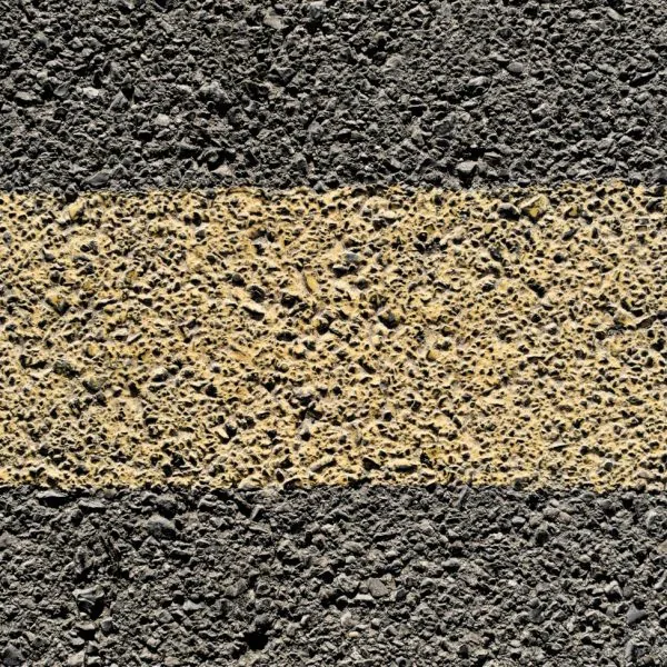A close-up of a faded yellow road line.