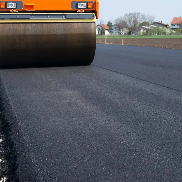 A roller flattens fresh asphalt