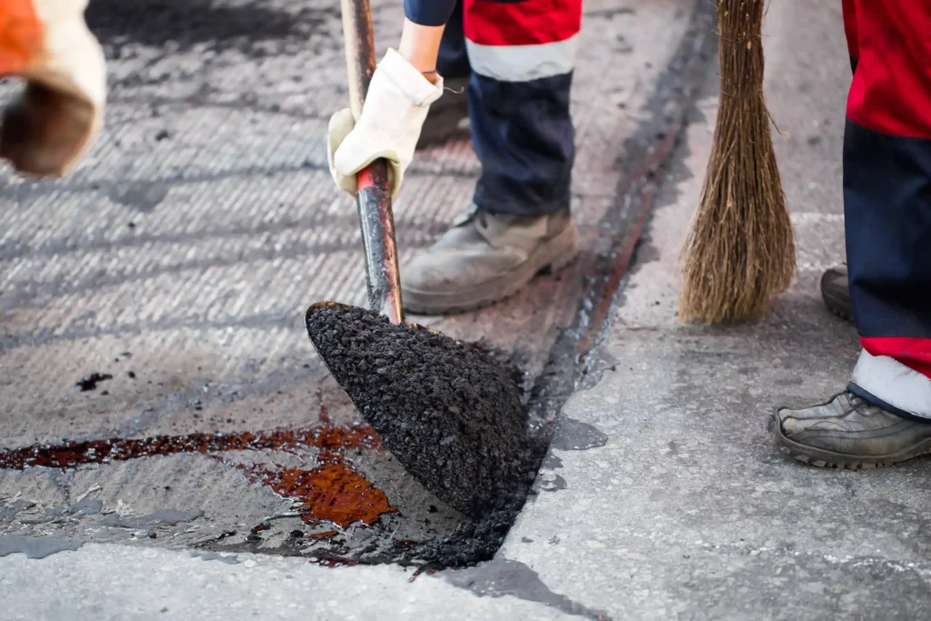 A contractor work to fill cracks with asphalt.