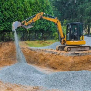 A worker adds gravel for soil stabilization to build a strong foundation for the new road project.