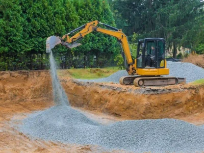 A worker adds gravel for soil stabilization to build a strong foundation for the new road project.